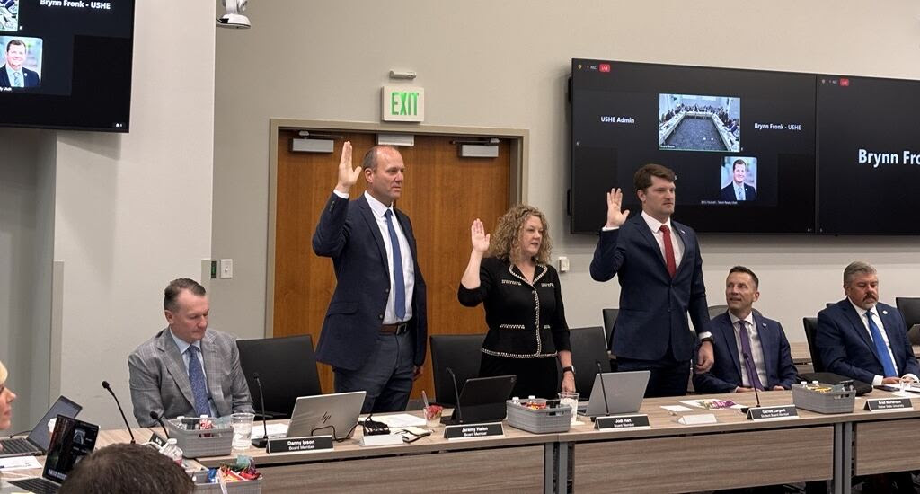 NASL Member Jodi Hart Sworn into Utah Board of Higher Education Three people stand with raised right hands being sworn in at a meeting room, while others sit at a table with laptops and nameplates. Two screens and photos are visible on the wall behind them.