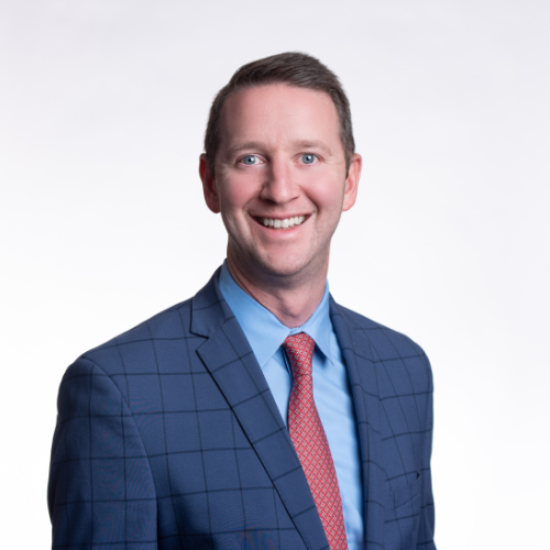 Mike Johnson - Sullivan and LeShane Inc A man in a blue checked suit, blue shirt, and red tie smiles at the camera against a plain white background.