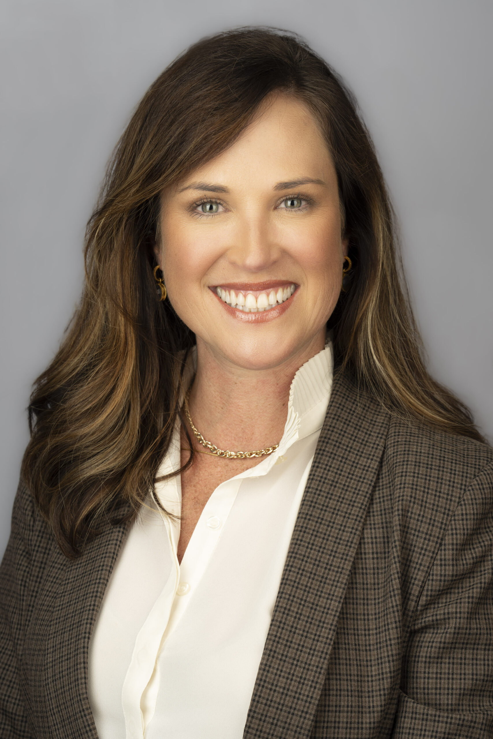Anna Richardson Headshot 2023 A professional headshot of a smiling woman wearing a white blouse under a brown patterned blazer.